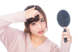 丸い手鏡を持った何かを困っている女性
