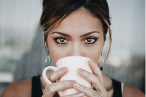 コップで飲み物を飲んでいる外国人の女性