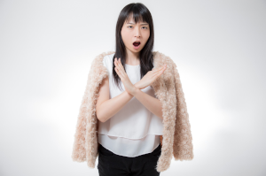 女性が胸当たりで大きなバツを腕で作っている