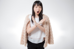 女性が胸当たりで大きなバツを腕で作っている