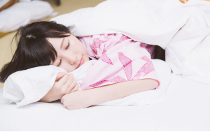 うつ伏せで枕を抱えながら寝ている女性