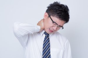 眼鏡をかけたスーツの男性が首を痛めている様子