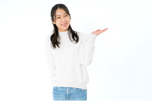 白い服を着た髪の長い女性が左手でどうぞとしている