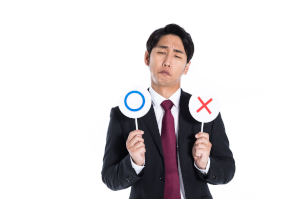 ○×プレートを持っているスーツの男性