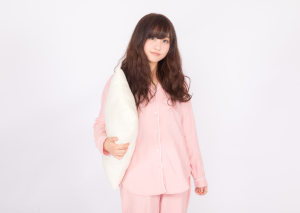 枕を持ってこっちを見ているパジャマを着た女性