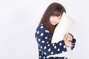 枕をぎゅーっとしているドット柄のパジャマを着た女性