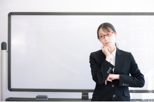 顎に手をあてながら考え事をしているスーツの女性