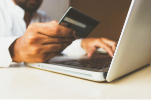 クレジットカードを持ちながらパソコンに何かを入力している