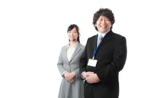 スーツを着た男性と女性がこちらをみてニッコリしている