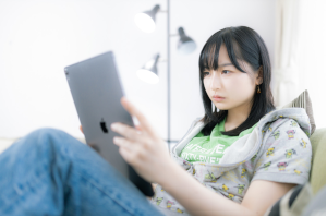ソファに座りながらタブレットを見ている女性