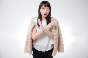 女性が胸あたりで大きな×を腕で作っている