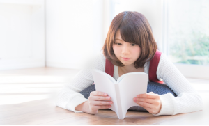 うつ伏せで本を読んでいる女性