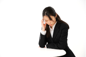 座って悩んでいるスーツを着た女性