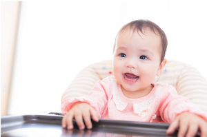 座っている赤ちゃんが口を開けて待っている様子