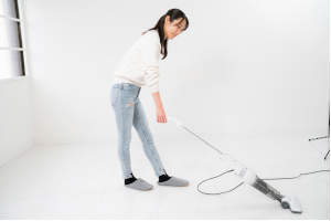 真っ白な部屋で掃除機をかけている女性