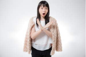 女性が胸あたりで大きな✕を腕で作っている