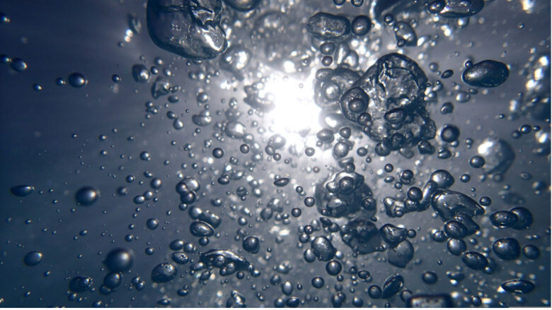 水中に漂う微細な泡が光に照らされている様子。