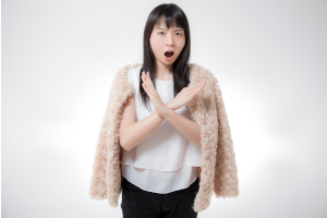 女性が胸あたりで大きな×を腕で作っている