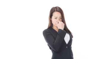 スーツを着た女性が臭いと鼻をつまんでいる