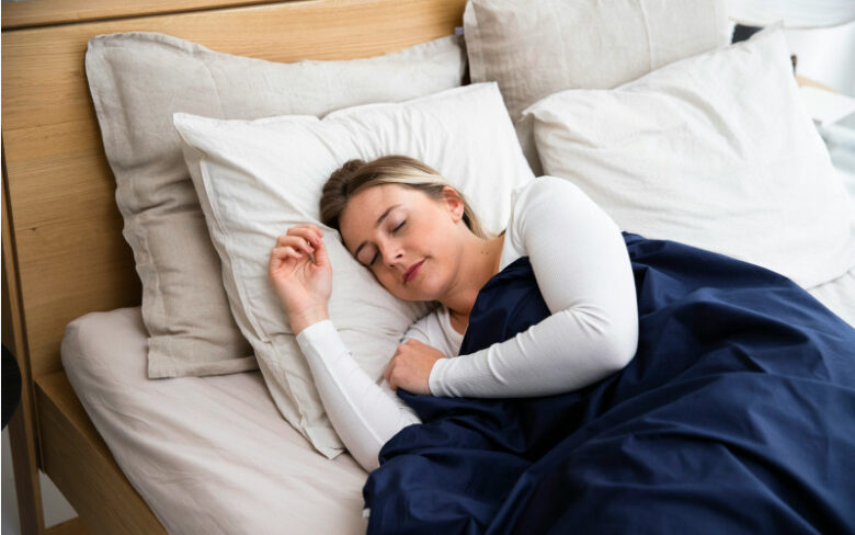 風邪や体調不良の時にベッドで青い毛布にくるまってゆっくりと休む女性