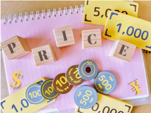 ノートの上にPRICEと書かれた積木とおもちゃのお金