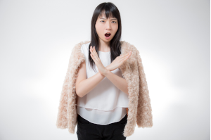 女性が胸あたりで大きな×を腕で作っている