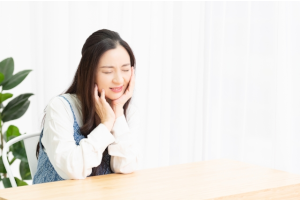 座っている女性が左頬を押さえて痛がっている