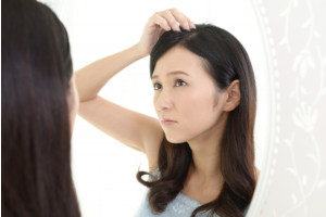 鏡を使って頭皮を見ている女性