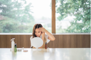 鏡の前で髪の毛をおさえている女性