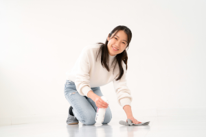 白い服を着た女性が雑巾で床を拭いている