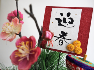 迎春と書かれた習字と梅の花
