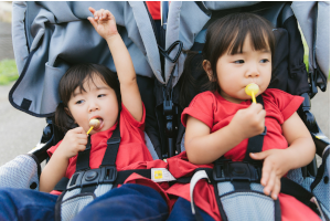 ベビーカーに乗って飴を舐めている2人の女の子