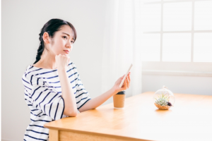 顎に手をあてて考え事をしている座っている女性