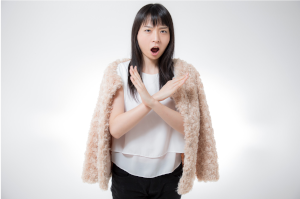 女性が胸あたりで大きな×を腕で作っている