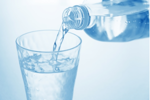 ペットボトルの水をコップに注いでいる