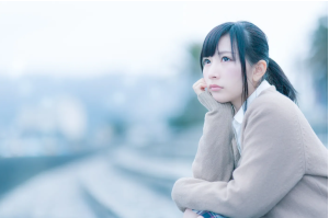 外で肘をついて考え事をしている女性