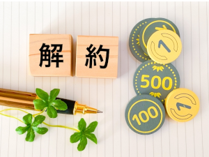 解約と書かれた2つの積木とボールペンとおもちゃのお金