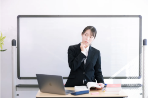 スーツを着た女性があごに手をあてて考え事をしている