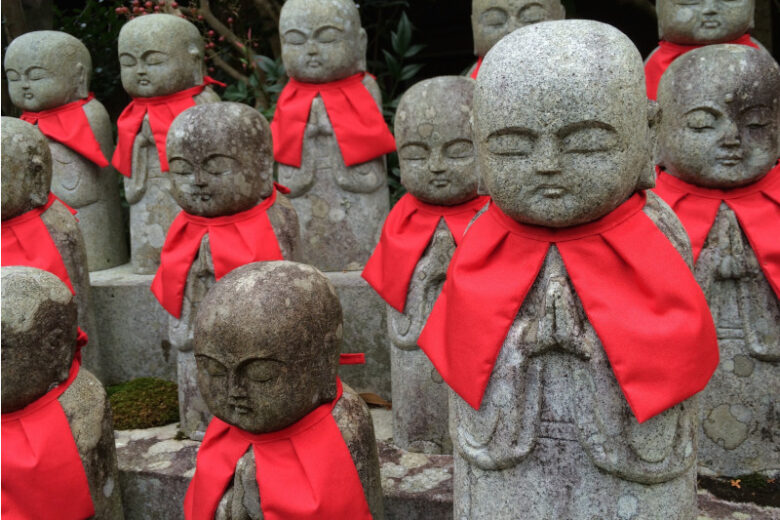 鮮やかな赤いよだれかけを身につけて並んで鎮座する複数のお地蔵さん