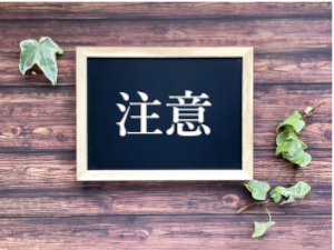 木の枠で囲まれた黒い板に注意と書かれている