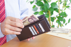 長財布から5,000円札を取り出す男性