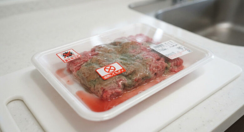 パックの中で変色しドリップが出た傷んだお肉と、加熱しても食べてはいけないことを示す警告アイコン