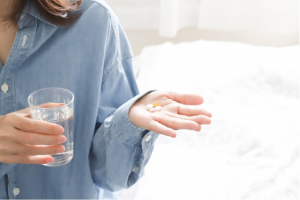 右手に水、左手に錠剤を持った女性