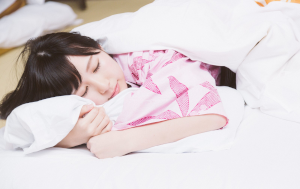 うつ伏せで寝ているピンクのパジャマを着た女性