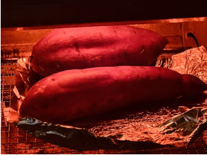 アルミホイルを敷いたトースターで焼かれる2本のさつまいも