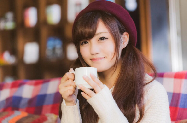 ココアを手にくつろぐ女性。温かい室内でリラックスしている様子。