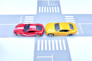おもちゃの交差点でぶつかっているおもちゃの赤い車と黄色の車