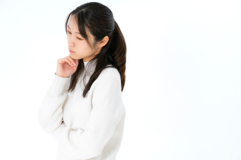 顎に手を当てて「本当かな?」と悩み、考え込んでいる女性