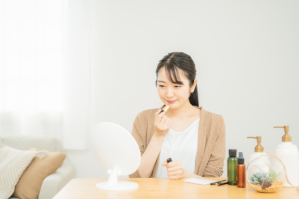 座って鏡の前に口紅を塗る女性