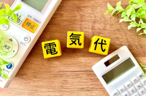 エアコンのリモコン･電卓の間に挟まれた電気代と1文字ずつ書かれた黄色の積木
